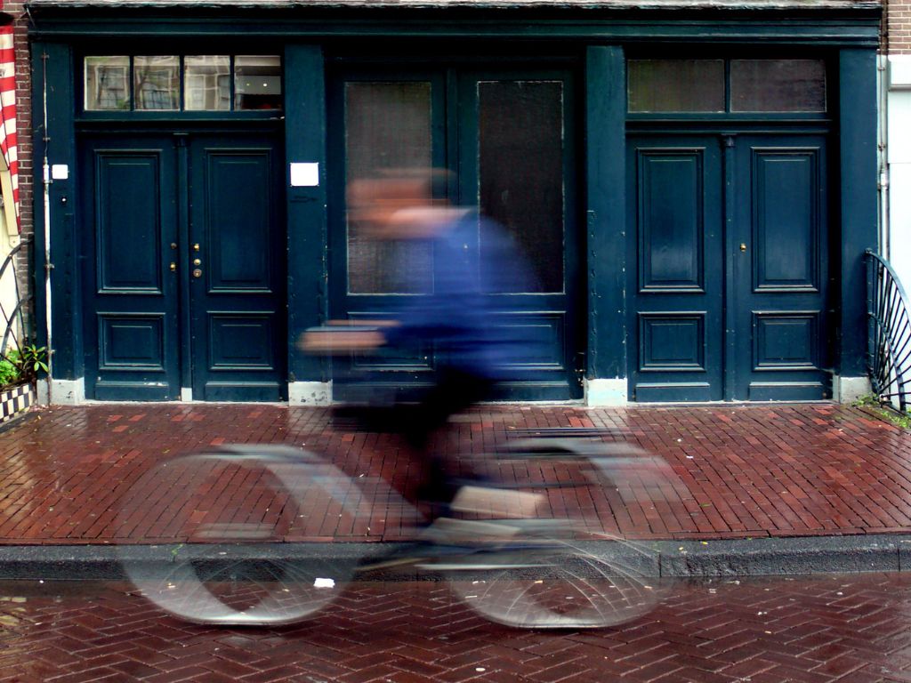 Man riding bike blurred image past The Anne Frank House